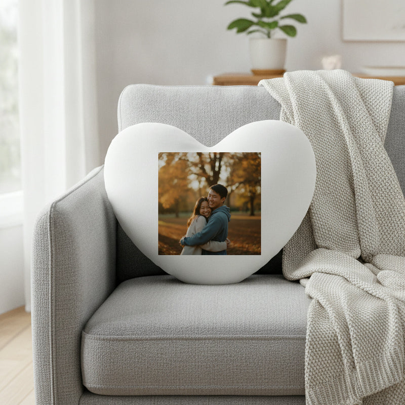 White heart-shaped photo cushion with a square photo print of a couple in the centre, on a grey sofa